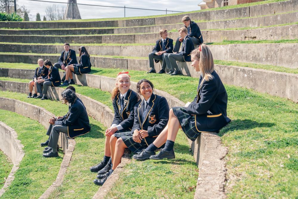 Photograph of students in their uniform seated in small groups in an amphitheater