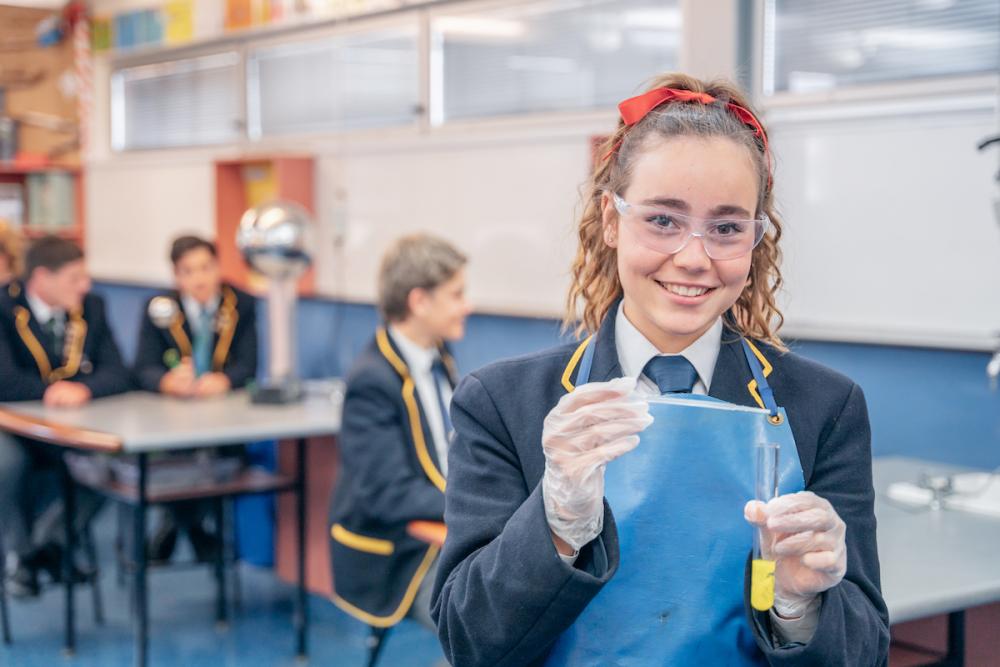 Photo of female student holding up science equipment