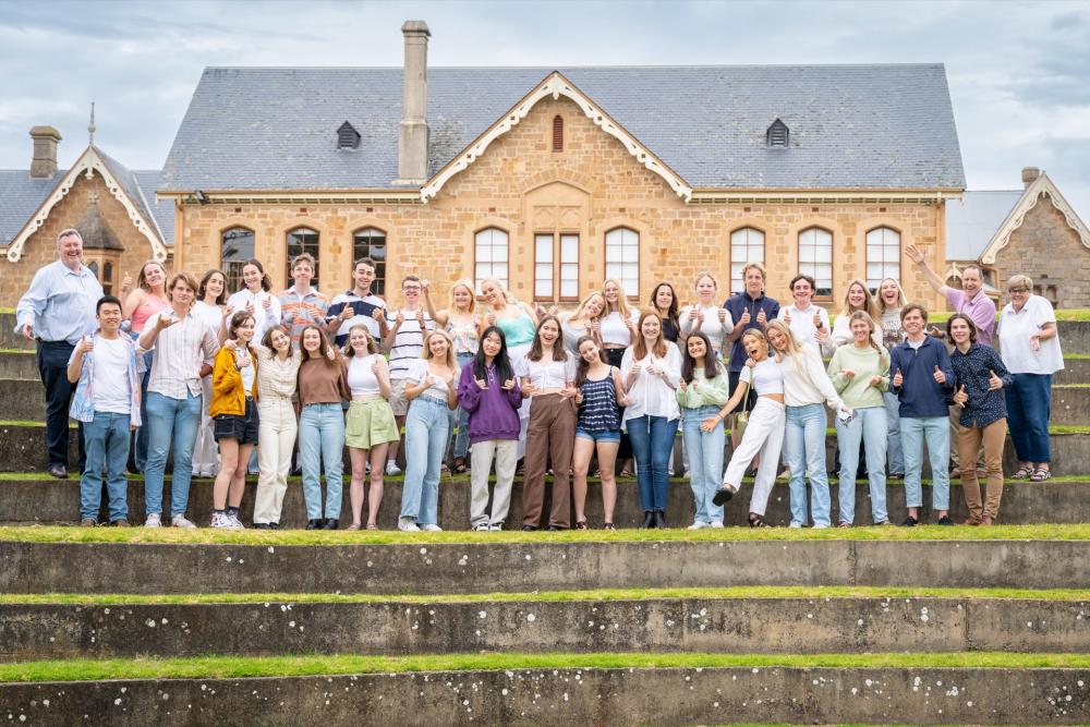 Photo of students and teachers sanding on steps outside of a school building